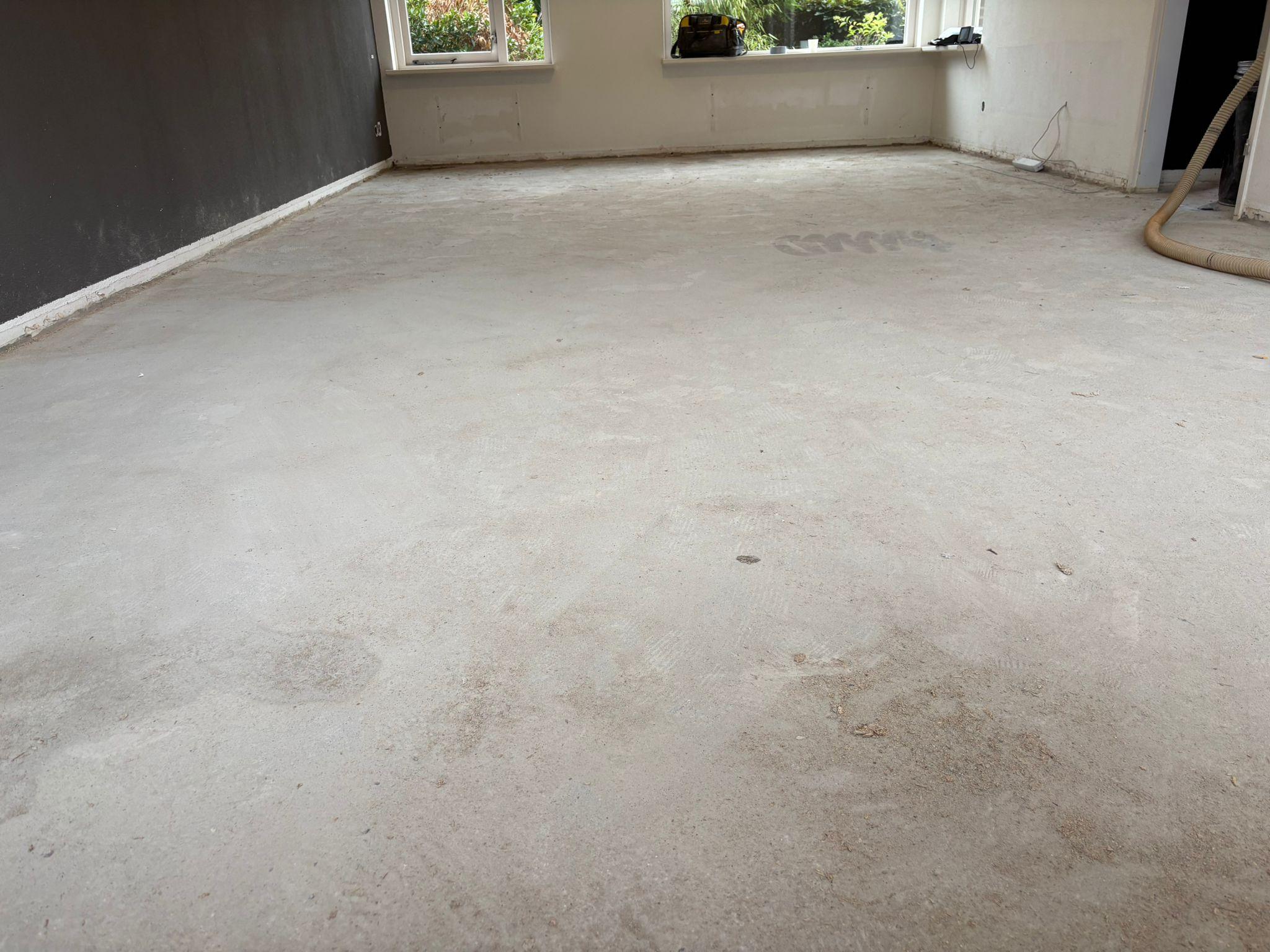 Lege woonkamer met kale zandcement dekvloer voor aanvang van het werk